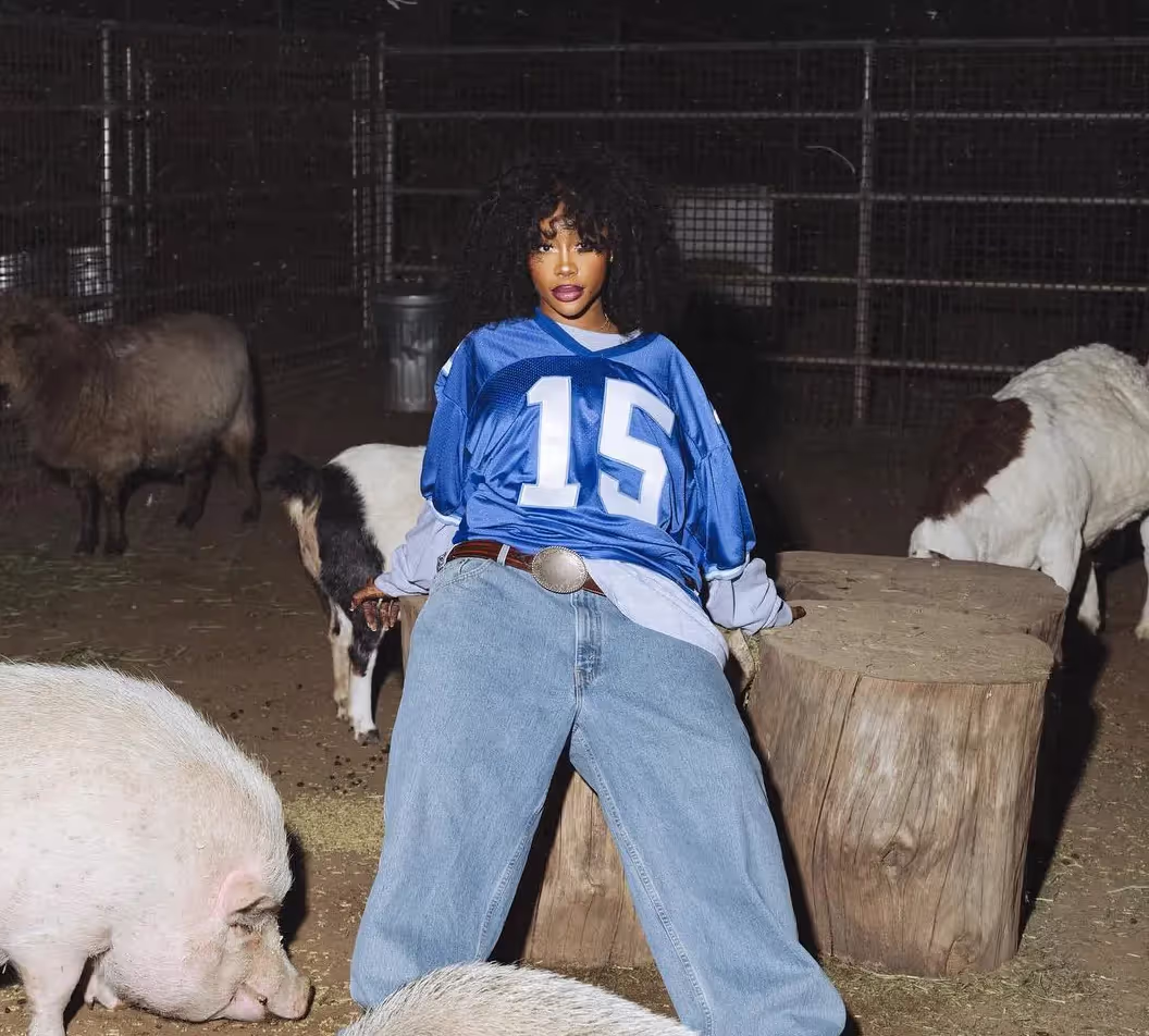 SZA wearing jeans and jersey with number '15' on a cover of new music friday, february 23 edition