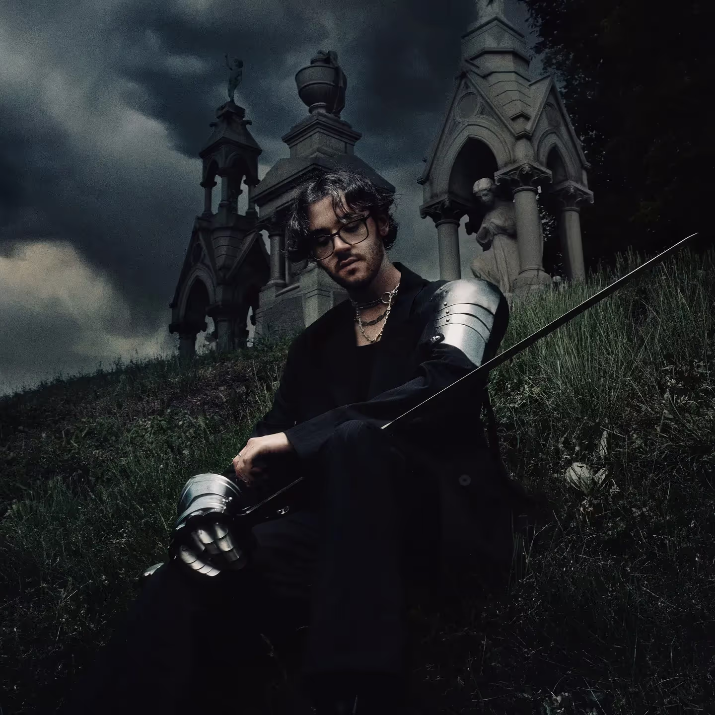 Chris Grey wearing black and silver armor in a foggy cemetery for the press kit of 'The Castle Never Falls'.