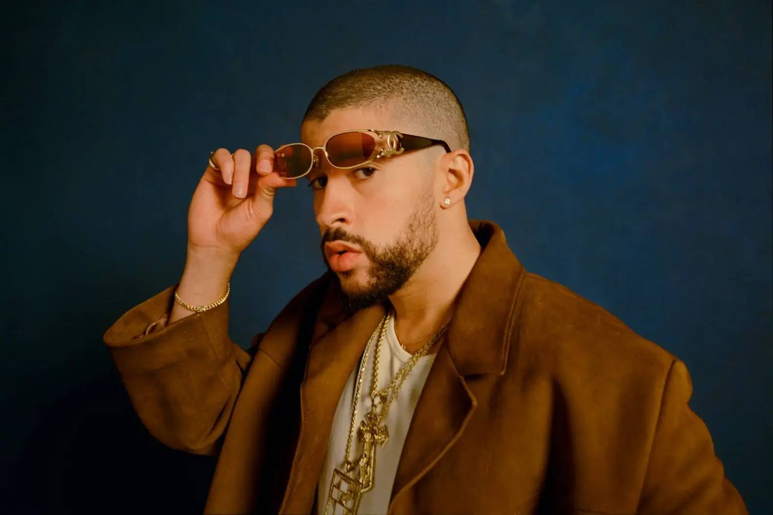 Bad Bunny wearing brown jacket and bright sunglasses for the release of "Nadie Sabe" a,bum