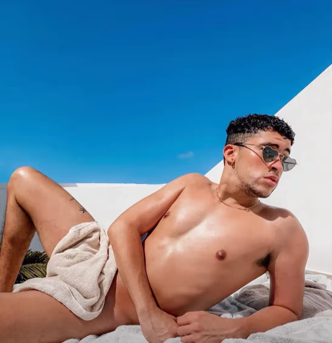 Bad Bunny covered just by the small towel and wearing heart-shaped sunglasses