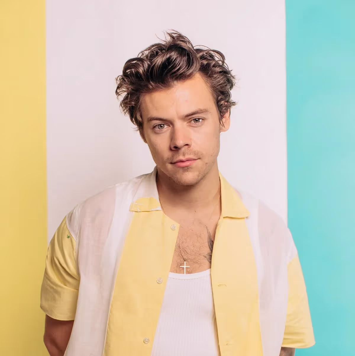 Harry Styles wearing stripped pink and yellow sport coat on a colorful background