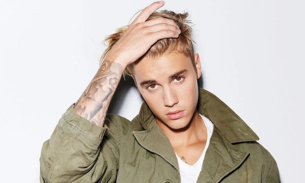 Justin Bieber portrait, wearing green coat on a light background