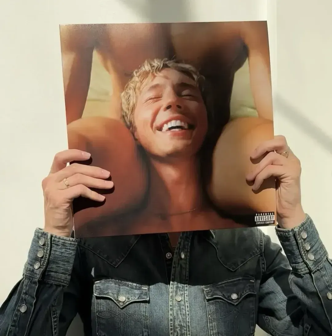 Troye Sivan holding his album "something to give each other"