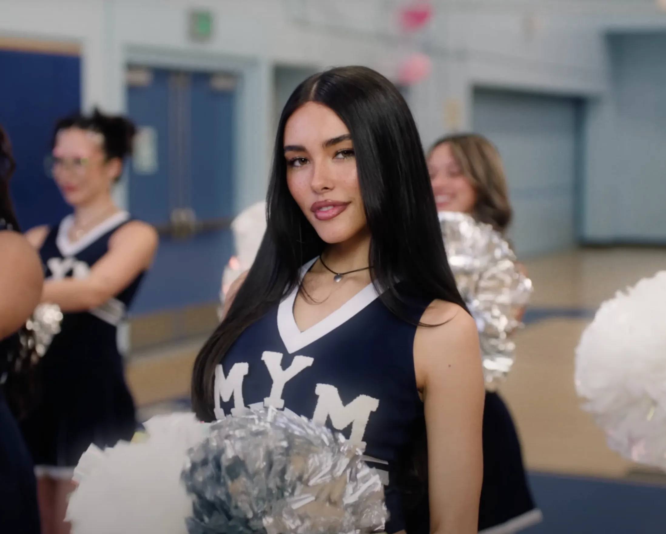 Madison Beer dressed in a white and blue cheerleading costume monogrammed with MYM for 'Make You Mine' music video