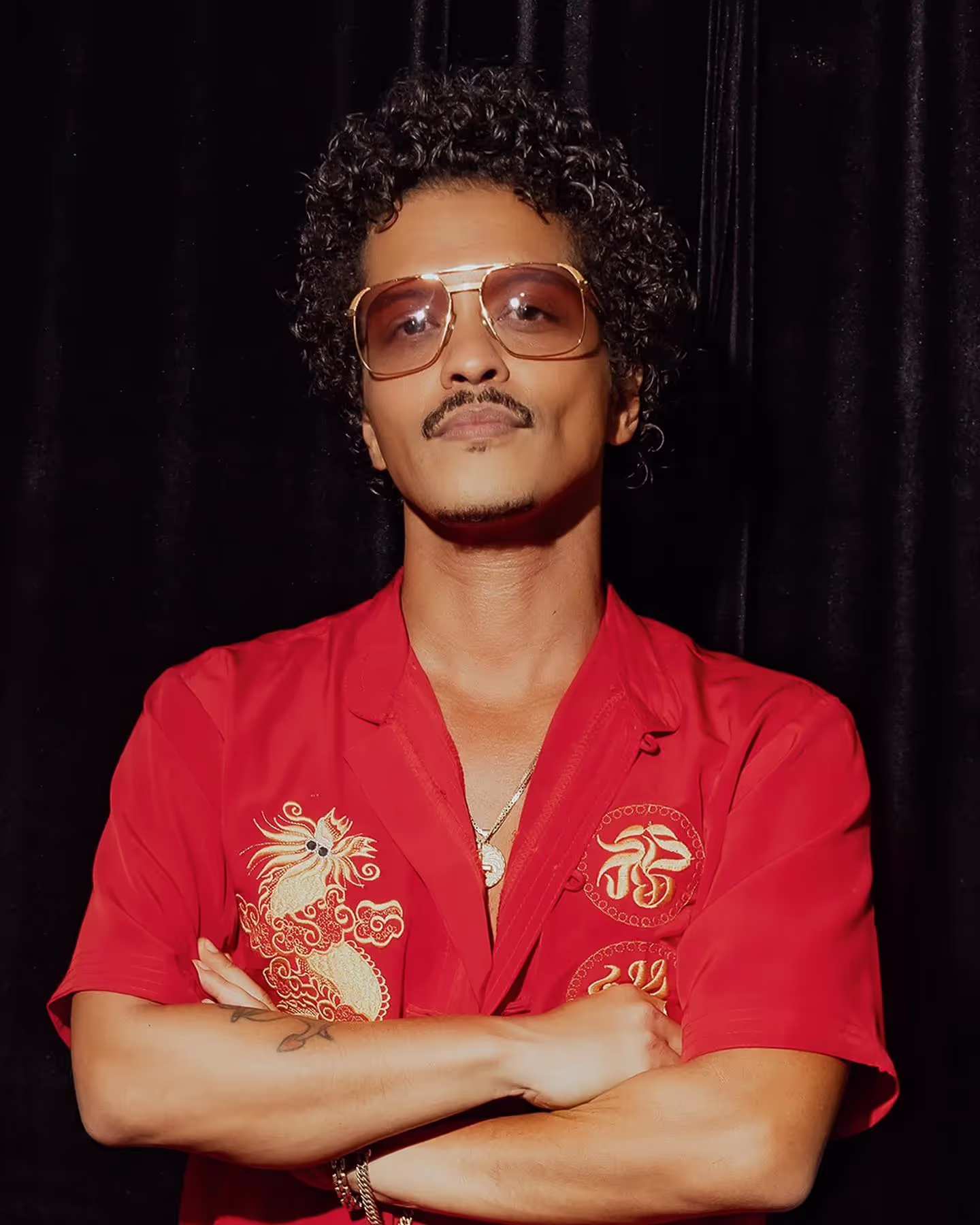 Bruno Mars wearing red shirt and glasses, 2024