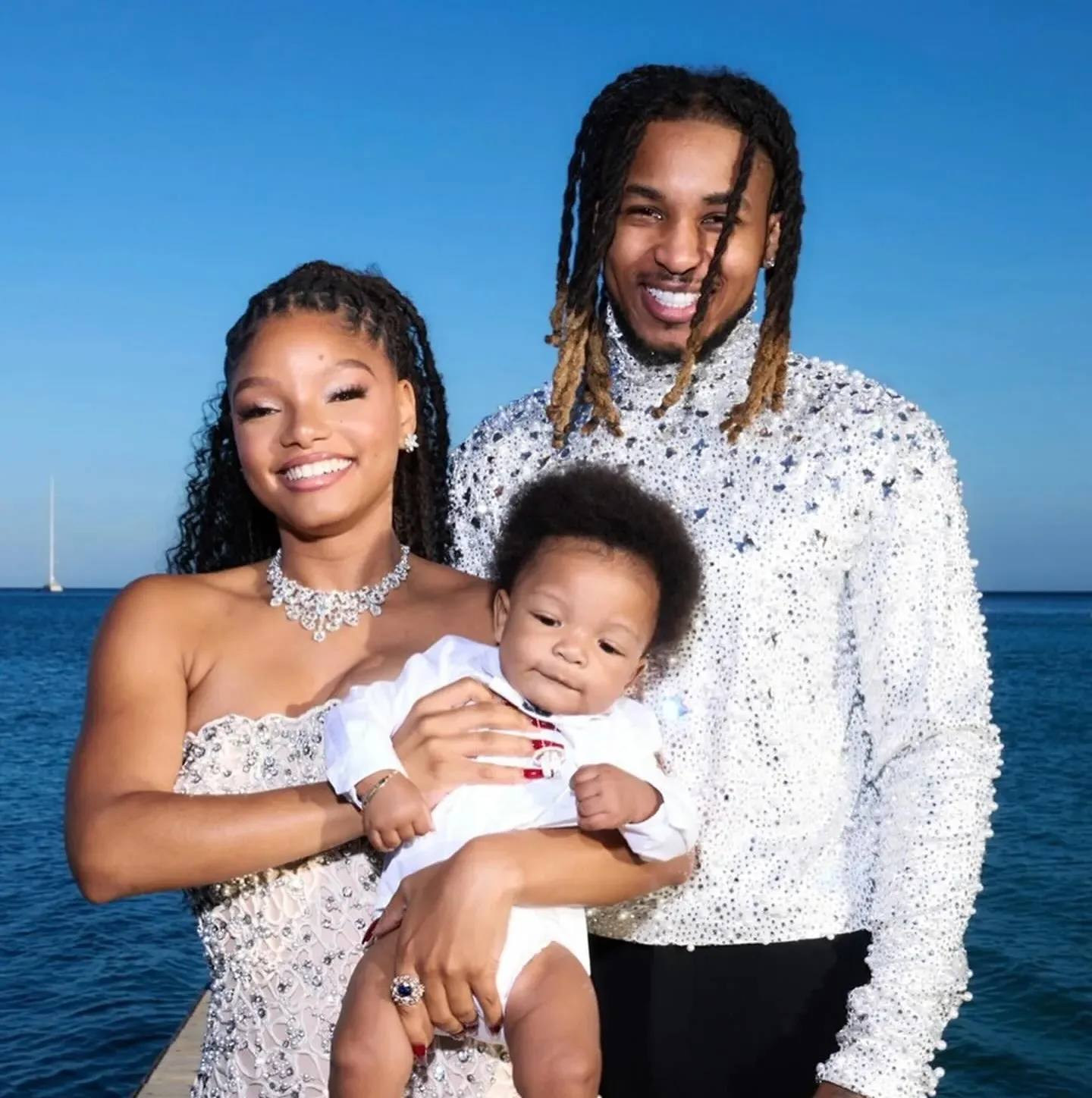 Halle Bailey wearing white lacy gown and DDG dressed in suit holding up Halo in Italy