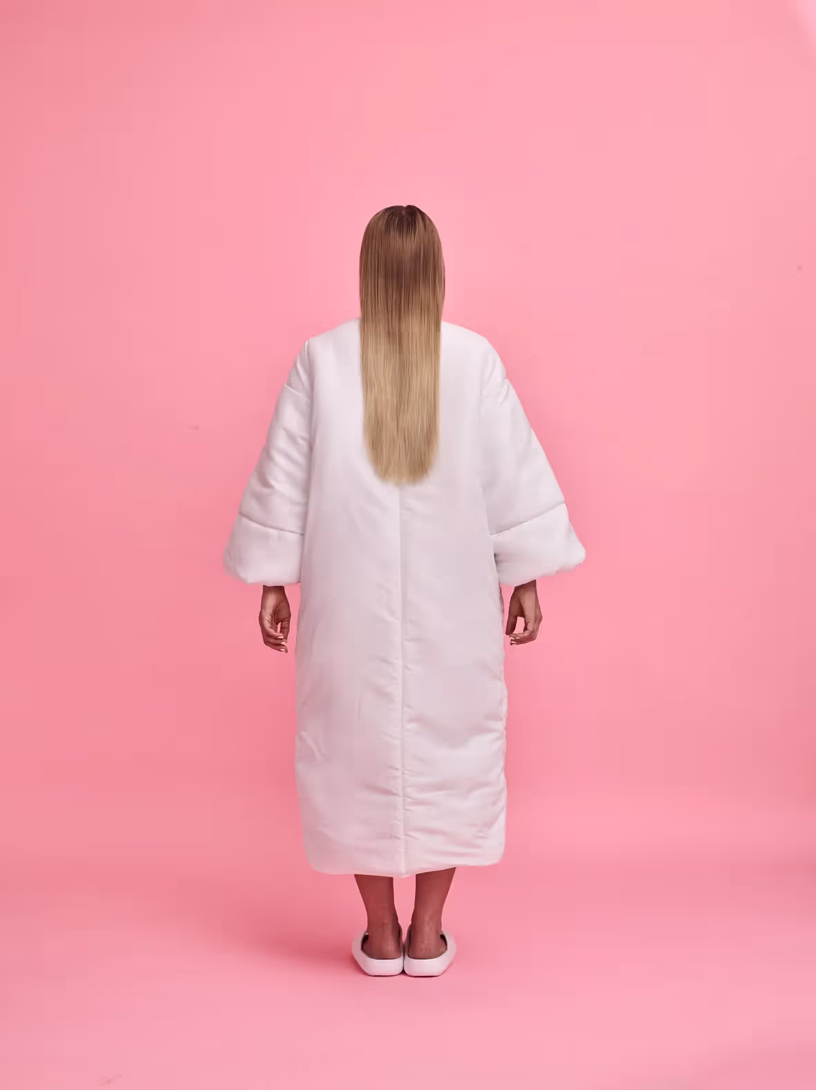 Cochis in full height in a white dress facing back on the pink background, photo credit Marko Rantanen