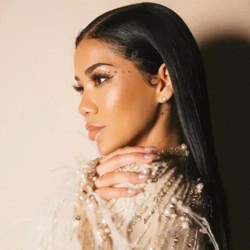 Jhene Aikos Porträt 2024, glattes Haar, neutrales Make-up und ein beigefarbenes Kleid mit Federn