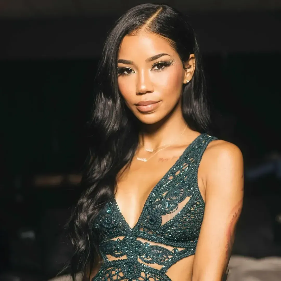 Jhene Aiko in deep decolte green beaded dress, wavy long black hair, artist bio/profile 2024