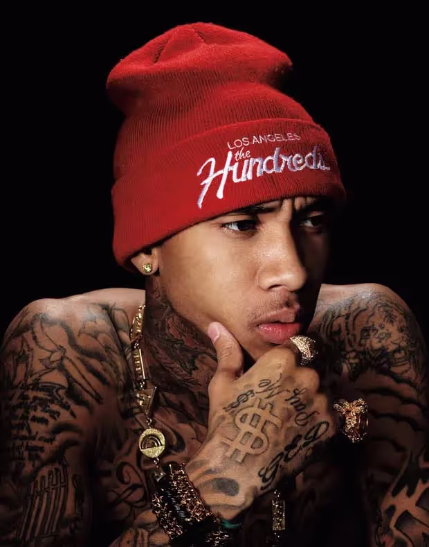 Tyga wearing a red hat, showcasing his tattoos, celebrating 'Taste' achieving RIAA Diamond status.