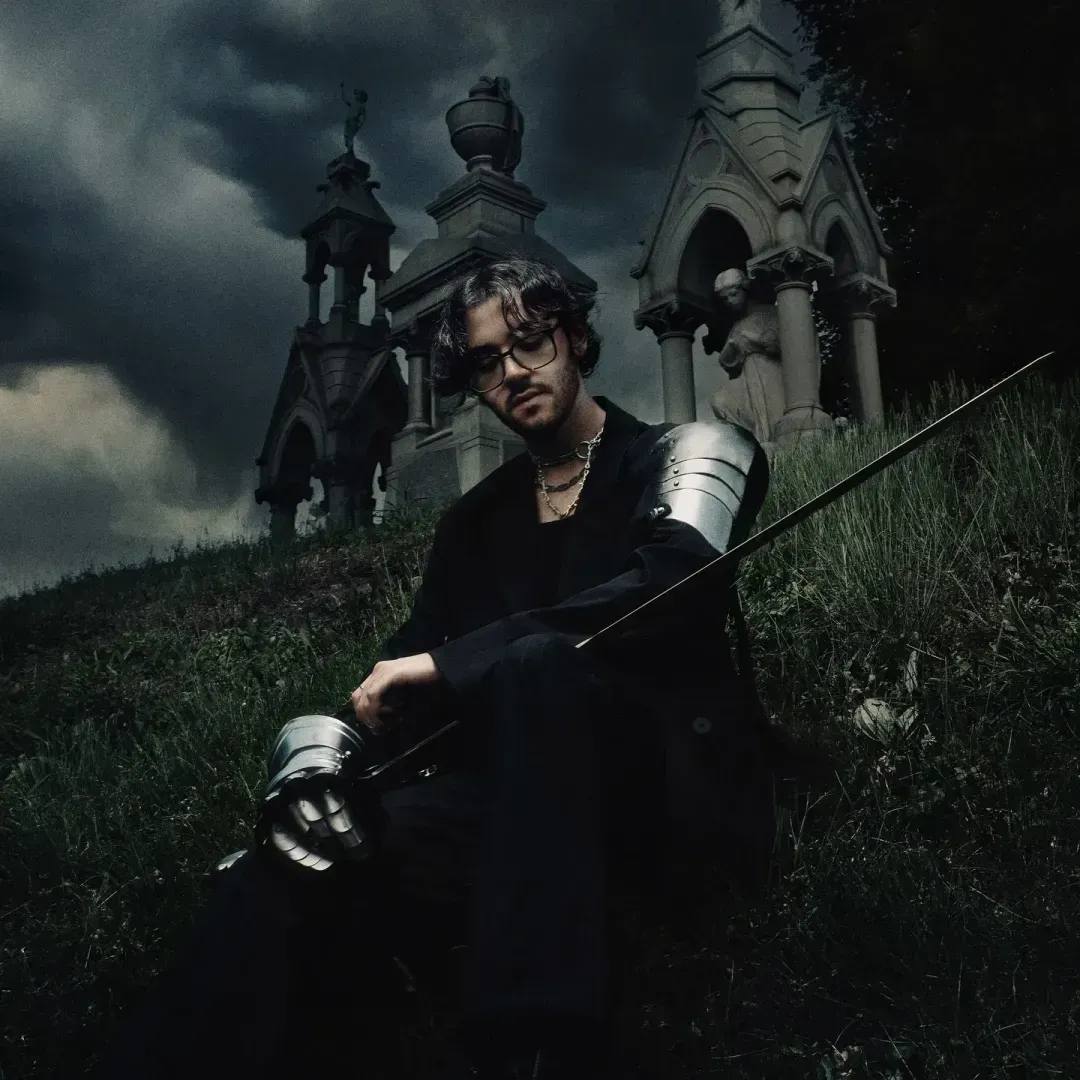 Chris Grey wearing black and silver armor in a foggy cemetery for the press kit of 'The Castle Never Falls'.