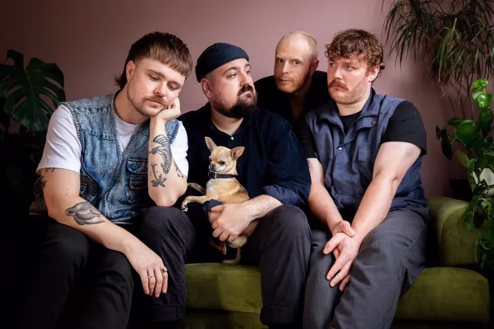 Adult Leisure members: Neil Scott, David Woolford, James Laing, Nathan Searle, sitting on the green velvet couch with small chihuahua.