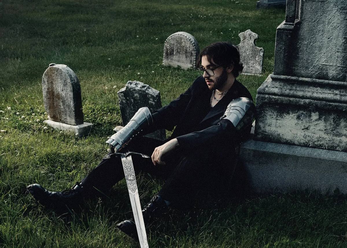 Chris Grey in armor, holding a sward, cemetery, 'The Castle' press photo - PopFiltr