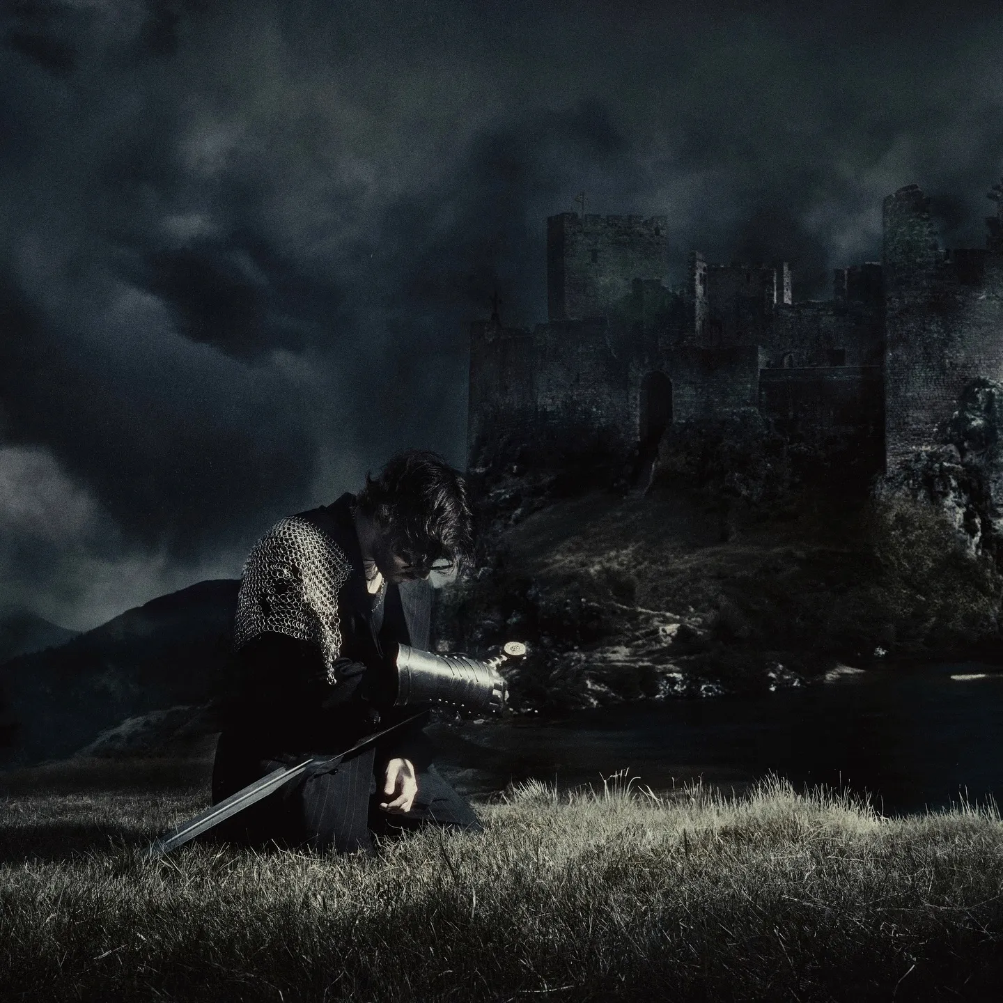 Chris Grey in armor, night sky, castle, press images for 'The Castle Never Falls'