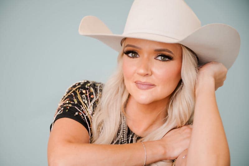 Billie Jo Jones in white hat and sparkly top, light blue background